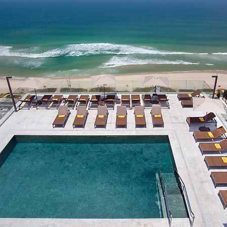 Windsor Marapendi Hotel Rio de Janeiro Eksteriør billede The photo shows a rooftop area with a swimming pool and several lounge chairs arranged around it. The pool has a clear blue surface, and the lounge chairs are positioned in a neat row, some with yellow cushions. In the background, you can see a beaut